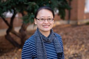 Woman wearing glasses and blue striped shirt smiling outside