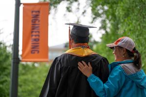 A woman puts her hand on a graduate's shoulder