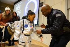 Leland Melvin signs a young community member's spacesuit
