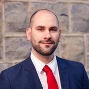 image of Aldo smiling wearing a red tie and blue jacket