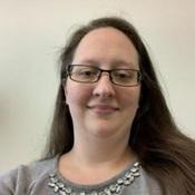woman with long dark hair wearing glasses and grey shirt