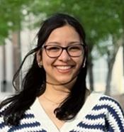 Image of woman with dark hair and glasses smiling outside