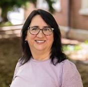 woman in lavender sweater with dark hair and glasses smiling