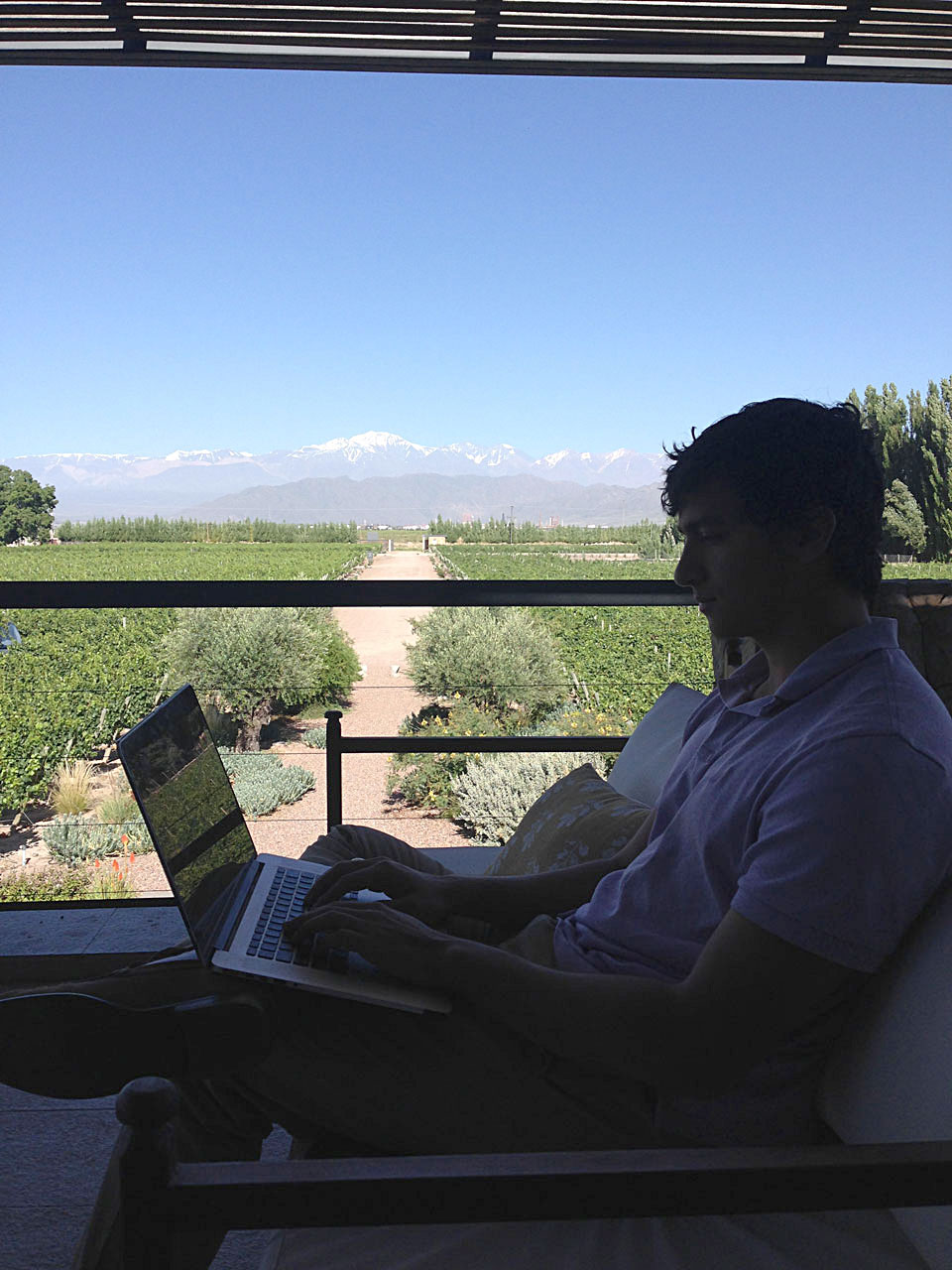 A student works on a computer next to a picture window with mountains in the background.