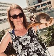 woman in flowered dress with small monkey on her shoulder