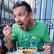 Image of man in green shirt eating food outside
