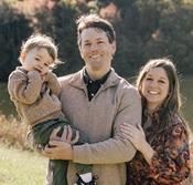 man, woman, and child smiling outside
