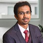 Image of man in suit coat and red tie wearing glasses