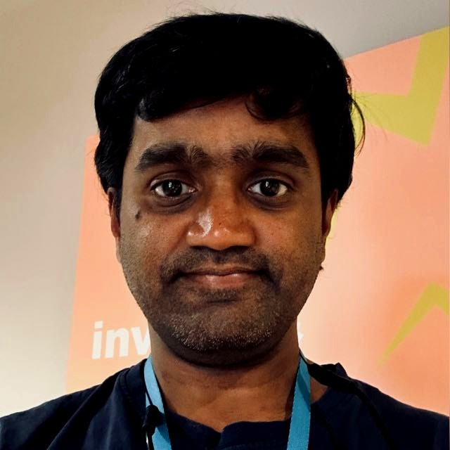 A man grins at the camera in front of inv sign