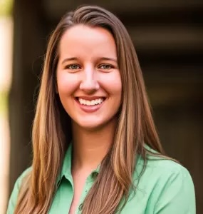 Woman stands outside smiling