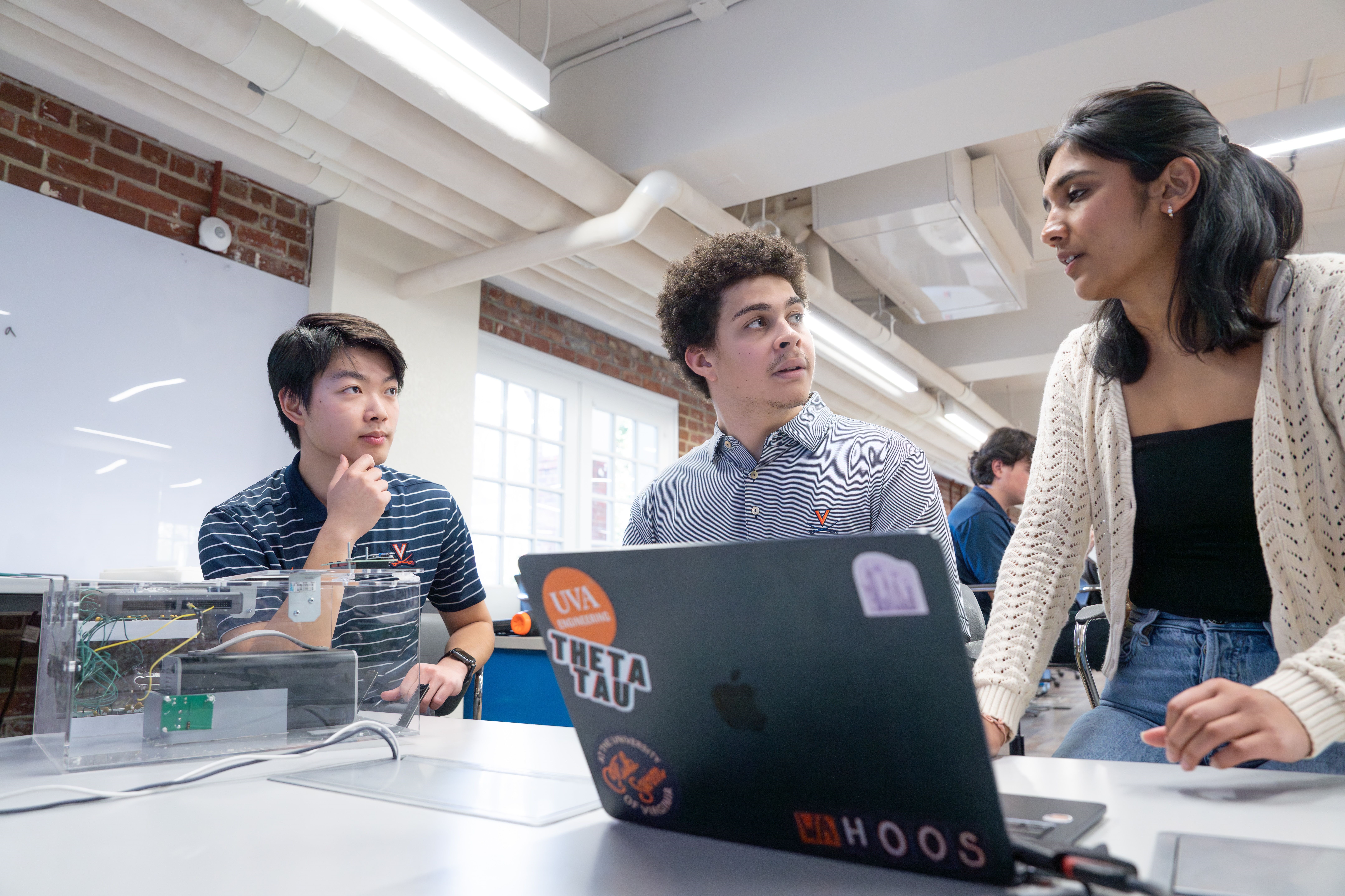 In addition to their computer engineering and electrical integration skills, Andy Chen, Preston Borden and Meghana Guttikonda, seated in discussion, all share competitive swim backgrounds in common. 