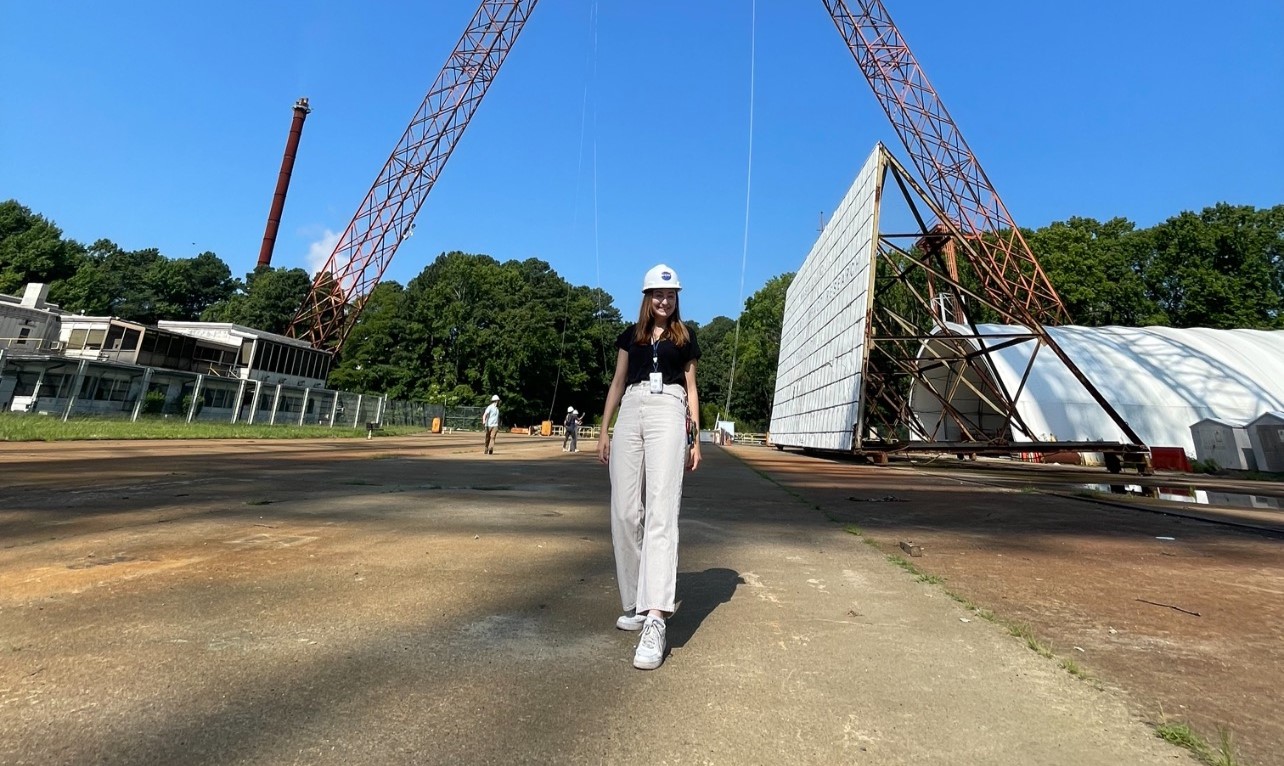 Small wears a hardhat as she walks through a NASA construction site.