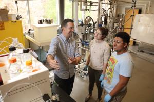 Professor interacting with students in chemical engineering lab