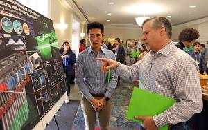 A graduate student discusses a research poster
