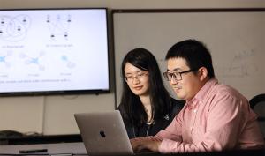Ph.D. computer science student Jing Ma (left) works with Jundong Li