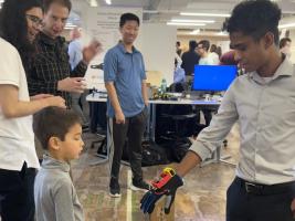 A student reaching a hand with an electronic glove out to a child