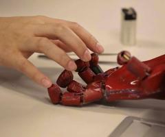 A human hand and robotic hand with fingers touching