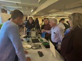 Faculty talking with students around a capstone demonstration