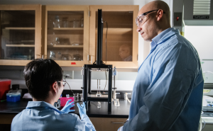 Evan Scott and postdoctoral researcher operate automated multi-inlet vortex mixer.