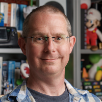 Image of man wearing glasses in a plaid pattered shirt smiling