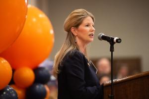 Side view of a woman speaking at a microphone