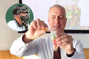 Professor pouring Nerds candies into a centrifuge tube full of Gobstoppers as part of a classroom demonstration.