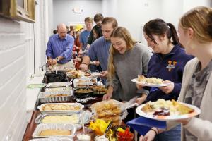 A line of people filling plates at a buffet dinner