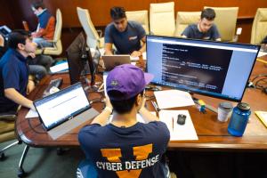 Several students working on computers around a conference table.