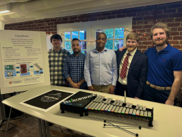Five student stand behind their capstone project that looks like a xylophone. 