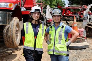 Two women engineers wearing hard hats and reflective vests at a construction job site
