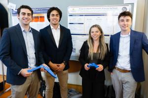 Students stand in front of their capstone poster