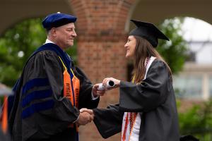 Chair Richard Kent presents a student with her diploma