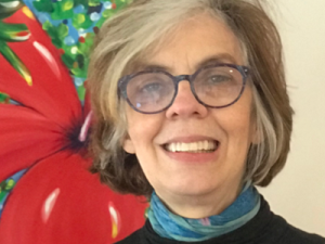 woman with glasses smiling in front of a painting
