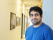 Man in blue sweater smiling in hallway