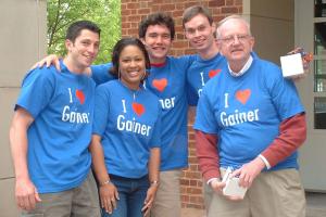 Four students wearing blue T-shirts printed with I [Heart] Gainer pose with Professor Gainer.
