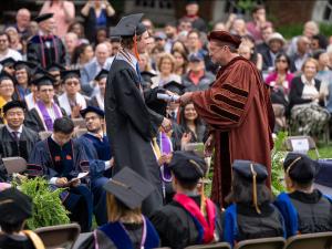 Chair Scott Acton presents a student with a diploma
