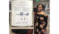 Rawan Osman stands beside the poster her capstone group designed to detail how their USB device works.