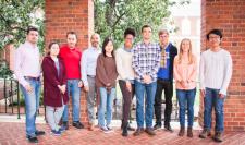 group of students standing against brick wall