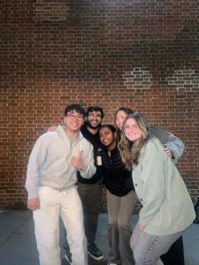 Five students in front of a brick wall