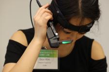 Woman wearing a headband with attached camera and lense lit up looks down