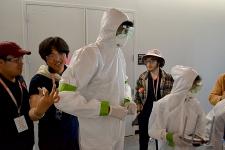 Students sign the white protective suit worn by another student.