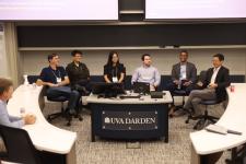 Panel of 6 people sit in chairs at the front of a classroom smiling and talking