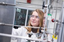 A woman in a white lab coat works on catalysis equipment