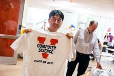 A student holds up a UVA Computer Science t-shirt