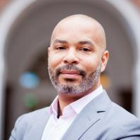 bald man with facial hair wearing a collared button-down and blazer