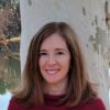woman wearing dark red sweater standing against a tree outside