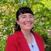 woman in red jacket wearing glasses smiling outside