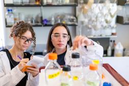 Two students examine glass containers in a chemical engineering lab